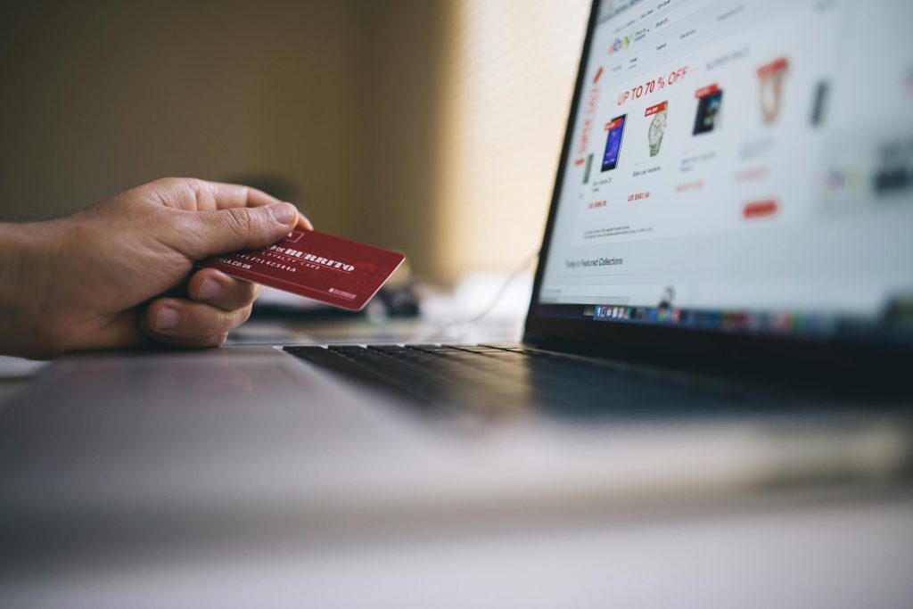 Top 10 Fastest Growing Consumer Product Categories in the UAE (2026) Person holding a credit card while shopping online on a laptop, indicating ecommerce transactions.